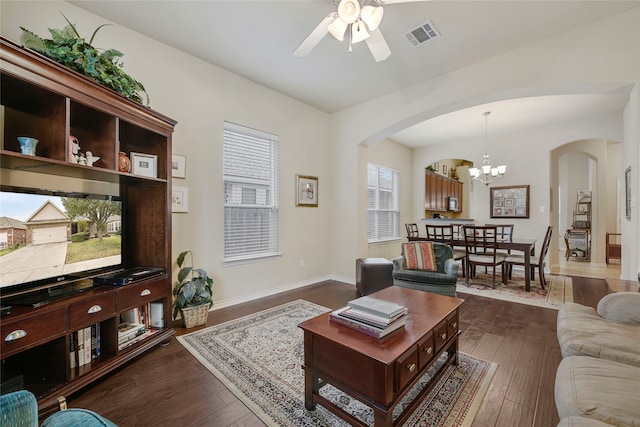 living room with dark hardwood / wood-style flooring and ceiling fan with notable chandelier