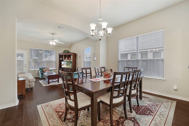 dining room with ceiling fan with notable chandelier, lofted ceiling, and dark wood-type flooring