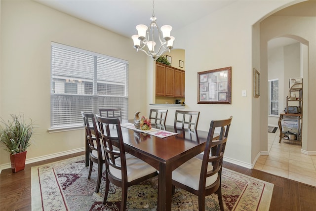 dining area with hardwood / wood-style flooring and an inviting chandelier