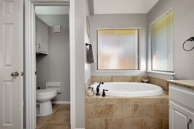 bathroom featuring tile patterned flooring, vanity, toilet, and tiled tub