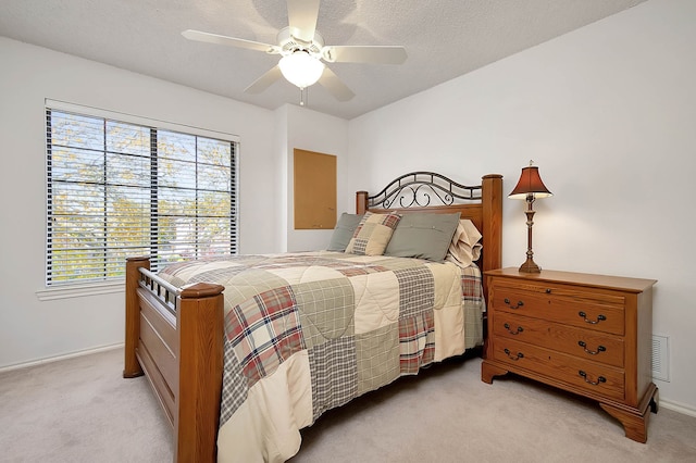 bedroom featuring light carpet, a textured ceiling, and ceiling fan