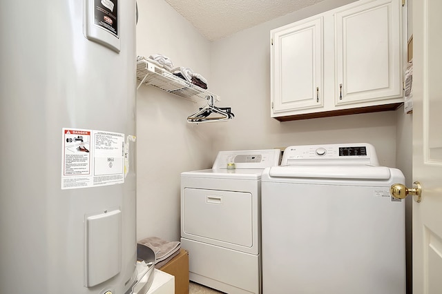 washroom featuring water heater, washer and clothes dryer, cabinets, and a textured ceiling