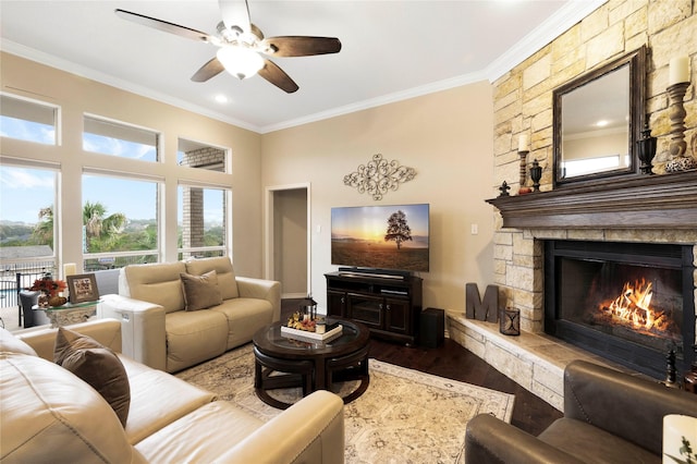 living room with a stone fireplace, ceiling fan, ornamental molding, and hardwood / wood-style flooring