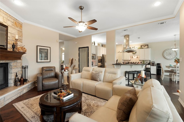 living room featuring ceiling fan, a fireplace, dark hardwood / wood-style floors, and ornamental molding