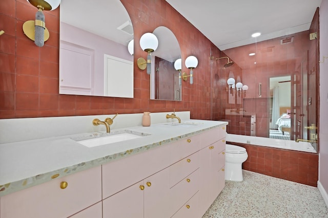 full bathroom with vanity, toilet, tile walls, and tiled shower / bath combo