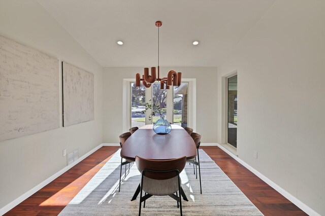 dining area with vaulted ceiling, dark hardwood / wood-style flooring, and an inviting chandelier