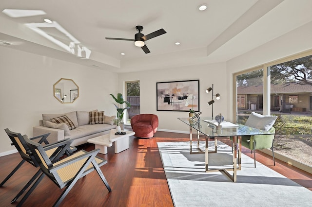 living room featuring hardwood / wood-style floors, ceiling fan, and a tray ceiling