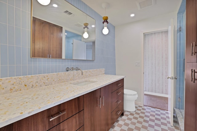 bathroom featuring vanity, a shower with door, decorative backsplash, toilet, and tile walls