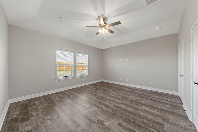 spare room featuring dark hardwood / wood-style floors, ceiling fan, and a raised ceiling