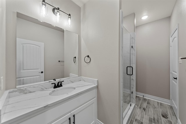 bathroom with hardwood / wood-style flooring, vanity, and a shower with door