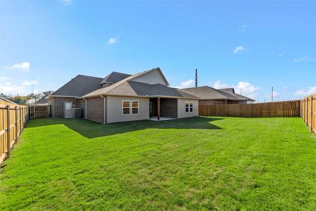 rear view of property with central AC unit and a yard