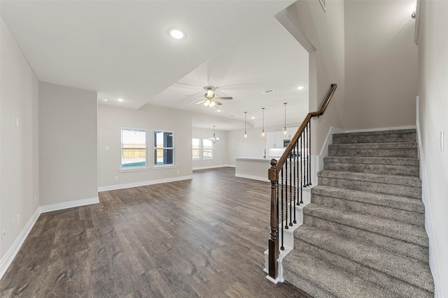 staircase with wood-type flooring and ceiling fan with notable chandelier