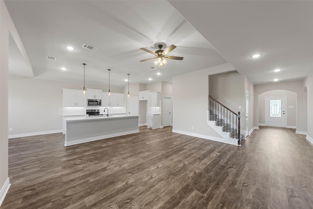 unfurnished living room featuring ceiling fan, sink, and dark hardwood / wood-style floors