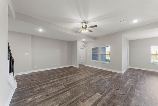 unfurnished living room featuring ceiling fan and dark wood-type flooring