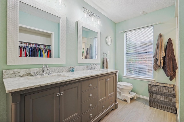 bathroom featuring vanity, a healthy amount of sunlight, toilet, and a textured ceiling