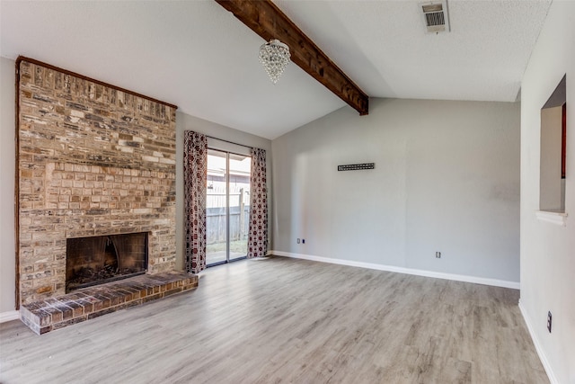 unfurnished living room with hardwood / wood-style floors, a fireplace, lofted ceiling with beams, and a textured ceiling