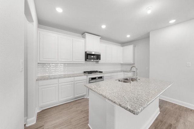 kitchen featuring white cabinetry, sink, stainless steel appliances, and a center island with sink