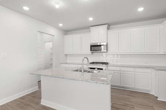 kitchen with stainless steel appliances, sink, a center island with sink, white cabinets, and hardwood / wood-style floors