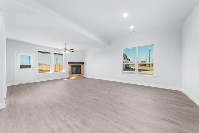 unfurnished living room with ceiling fan, a fireplace, a healthy amount of sunlight, and light hardwood / wood-style flooring