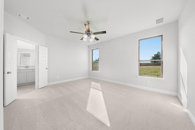 unfurnished bedroom with connected bathroom, ceiling fan, sink, and light carpet