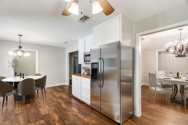 kitchen featuring white cabinets, decorative light fixtures, stainless steel appliances, and wooden counters