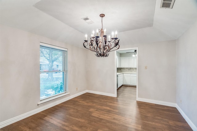 unfurnished dining area with ceiling fan with notable chandelier, vaulted ceiling, and dark wood-type flooring