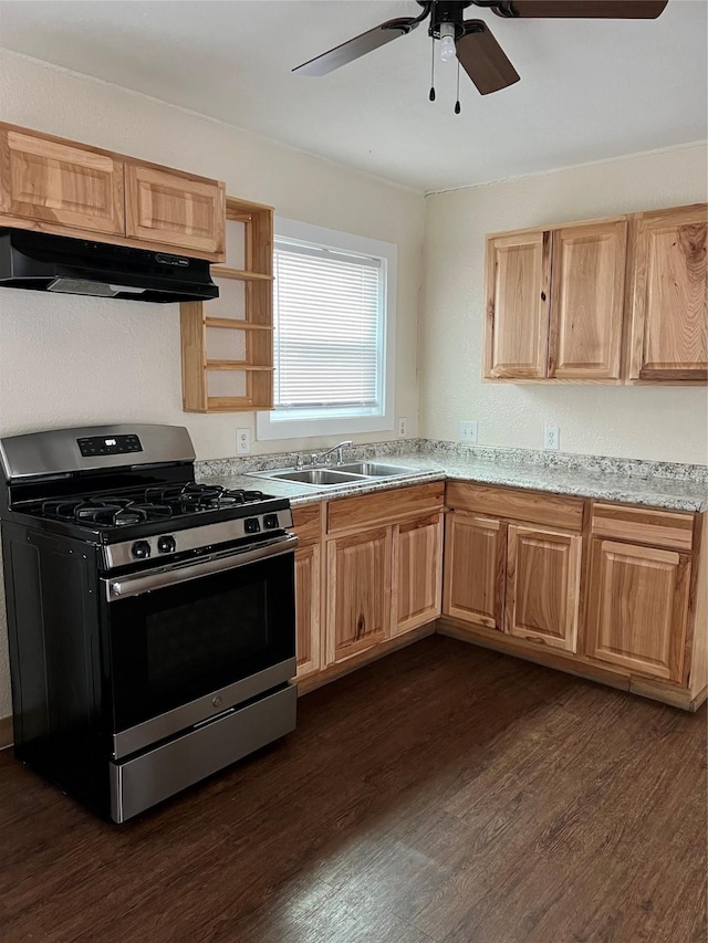 kitchen featuring light stone countertops, stainless steel gas range oven, ceiling fan, dark wood-type flooring, and sink