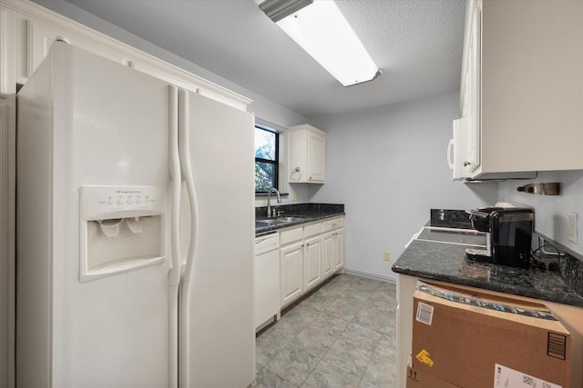 kitchen with white cabinets, a textured ceiling, white appliances, and sink