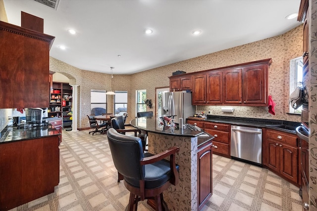 kitchen with decorative light fixtures, a kitchen island, a breakfast bar area, and appliances with stainless steel finishes