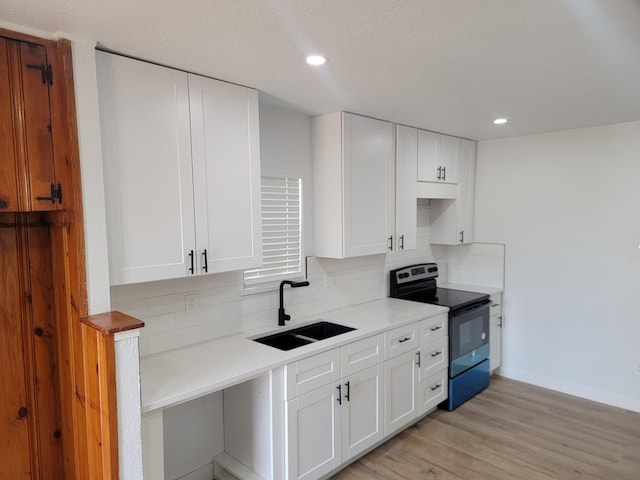 kitchen with sink, white cabinets, stainless steel electric stove, light hardwood / wood-style floors, and backsplash