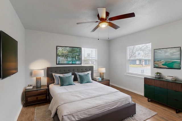 bedroom featuring ceiling fan, multiple windows, and light hardwood / wood-style flooring