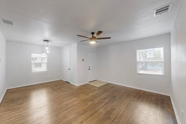 empty room with wood-type flooring, ceiling fan, and a textured ceiling