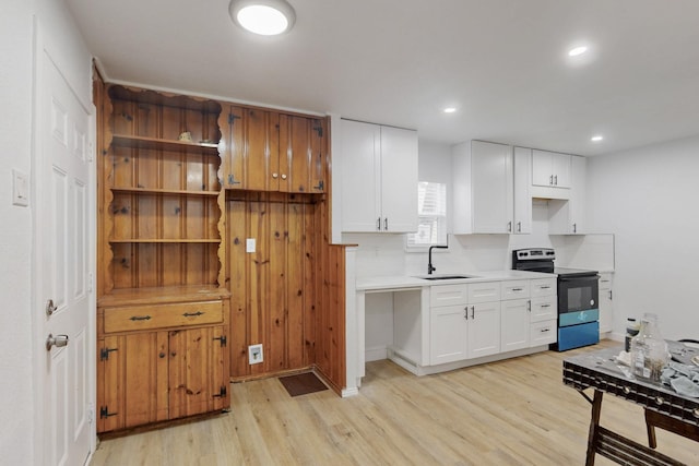 kitchen with white cabinetry, light wood-type flooring, sink, and electric range