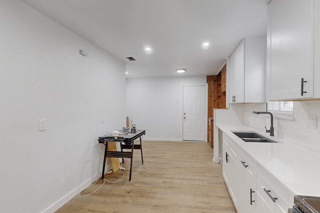 kitchen with sink, white cabinetry, light hardwood / wood-style flooring, electric stove, and backsplash