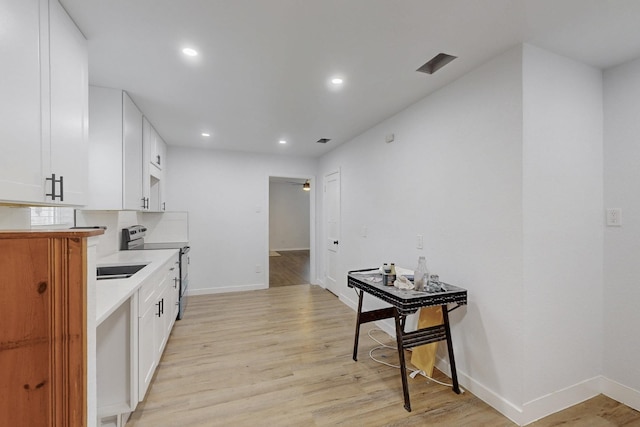 kitchen featuring white cabinetry, stainless steel range with electric stovetop, ceiling fan, and light hardwood / wood-style floors