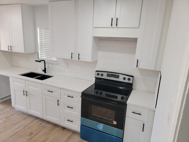 kitchen featuring sink, stainless steel range with electric stovetop, white cabinetry, light hardwood / wood-style floors, and decorative backsplash