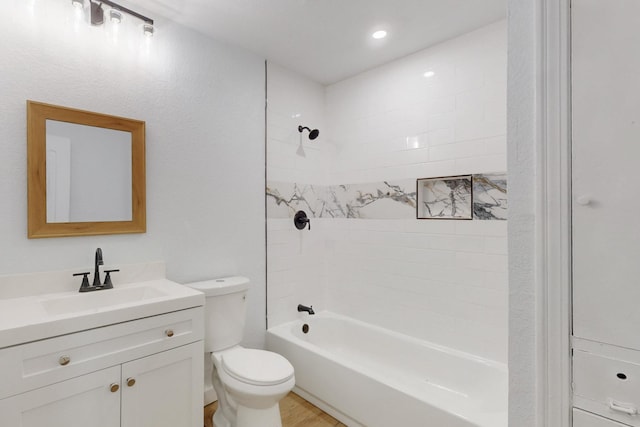 full bathroom featuring tiled shower / bath combo, vanity, and toilet