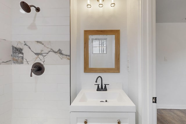 bathroom featuring hardwood / wood-style flooring, vanity, and tiled shower