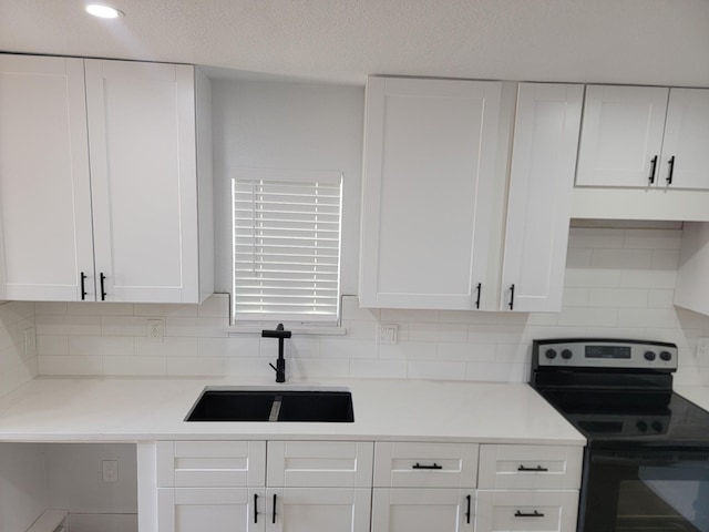 kitchen featuring range with electric cooktop, sink, decorative backsplash, and white cabinets