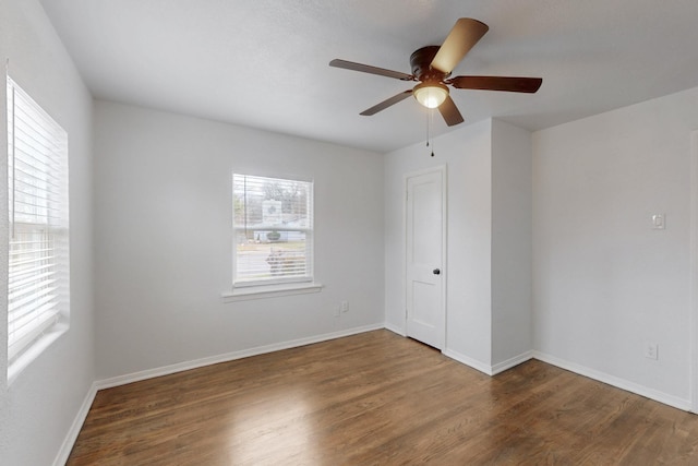 empty room with ceiling fan, a healthy amount of sunlight, and dark hardwood / wood-style flooring