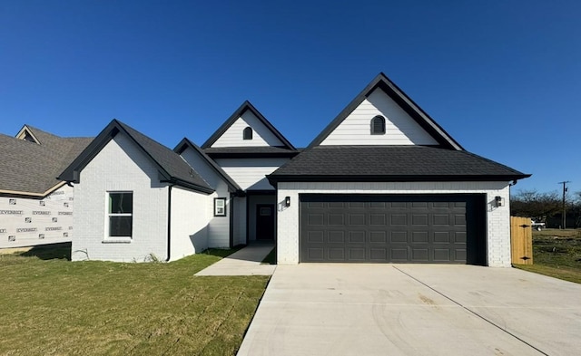 view of front of house featuring brick siding, roof with shingles, concrete driveway, a garage, and a front lawn