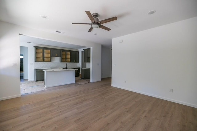 unfurnished living room featuring ceiling fan, light wood-type flooring, and sink