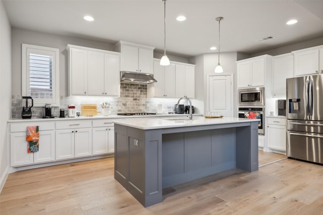 kitchen featuring appliances with stainless steel finishes, sink, pendant lighting, white cabinetry, and an island with sink