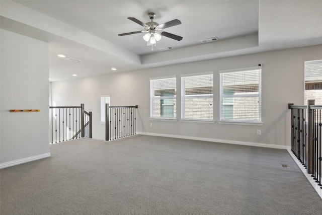 carpeted spare room with ceiling fan and a tray ceiling