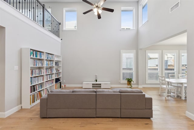 living room with a high ceiling, light hardwood / wood-style floors, and ceiling fan