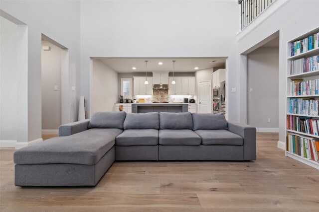 living room featuring built in features, light hardwood / wood-style flooring, and a high ceiling