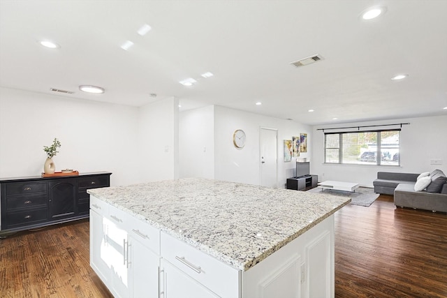 kitchen featuring white cabinets, dark hardwood / wood-style floors, a center island, and light stone countertops