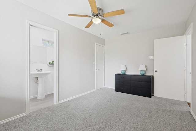 bedroom with connected bathroom, light colored carpet, and ceiling fan