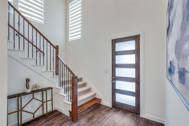 foyer with plenty of natural light, dark hardwood / wood-style floors, and a towering ceiling