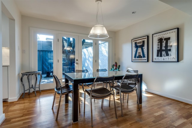 dining space with wood-type flooring, a wealth of natural light, and french doors